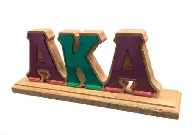 Wooden desk plaque featuring acrylic pink and green letters "AKA," perfect for sorority and fraternity Greek gear.